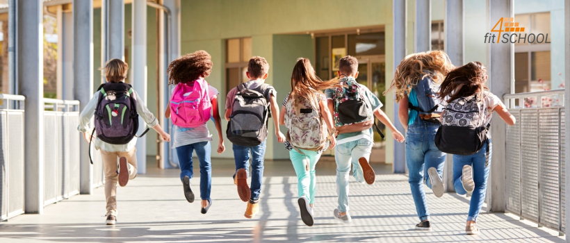 Kinder und Jugendliche mit Rucksäcken laufen fröhlich in ein Schulgebäude. Das Bild steht für das Projekt fit4SCHOOL, das Schüler:innen durch psychotherapeutische Unterstützung direkt an Schulen stärkt.